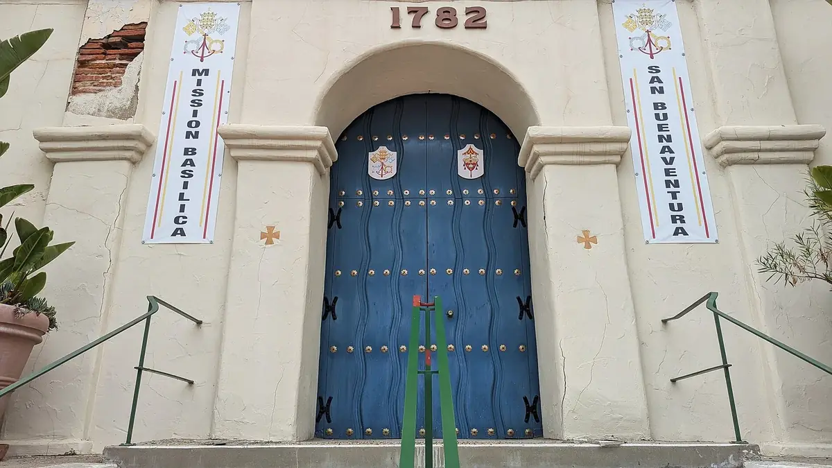 The blue wooden doors of Mission San Buenaventura under its 1782 date stone