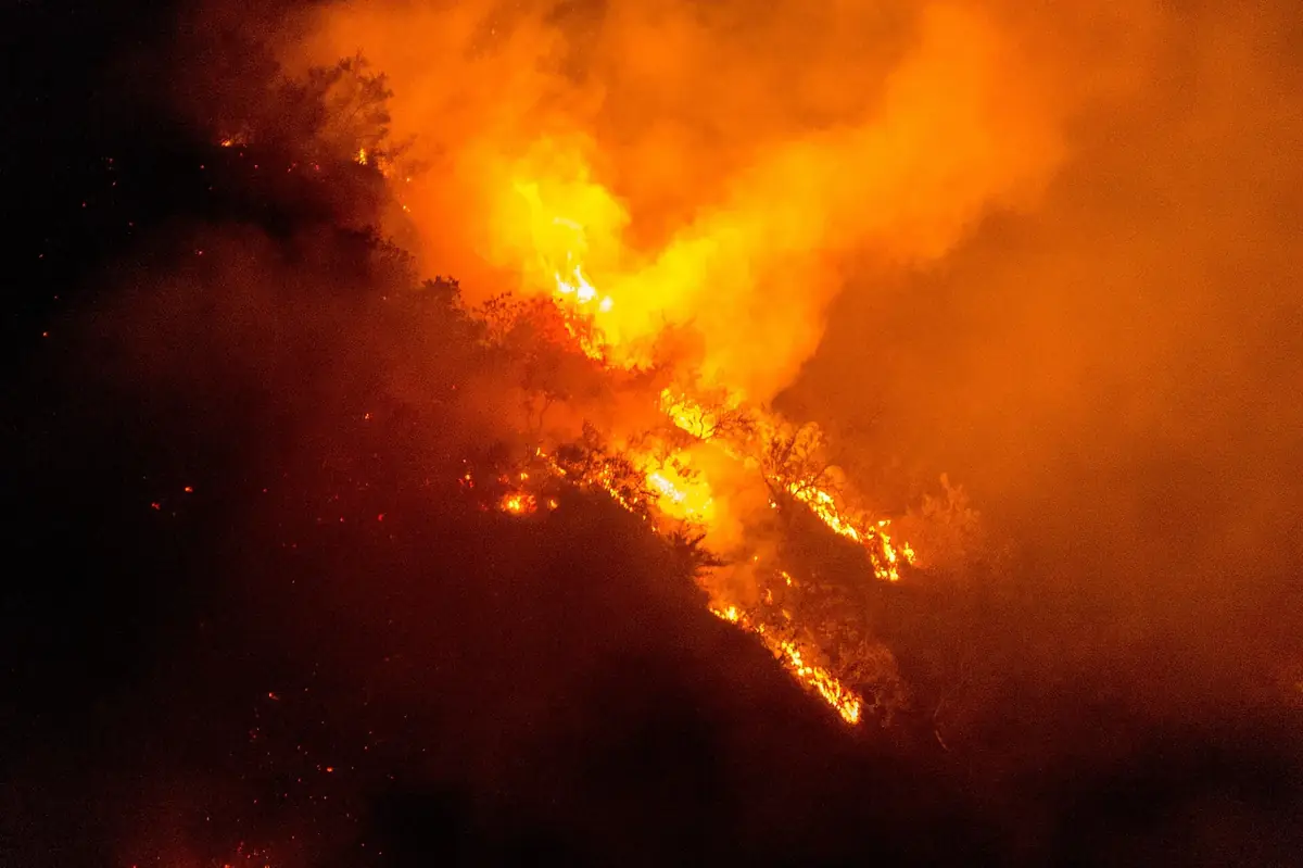 Wildfire flames running down a dark hillside at night